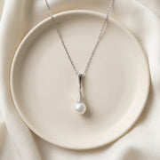Pearl necklace on a white plate with a soft beige background